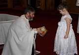 Fr. John presents Caroline with a Liturgy Book and an Icon of her Patron Saint at the conclusion of the Baptism Service